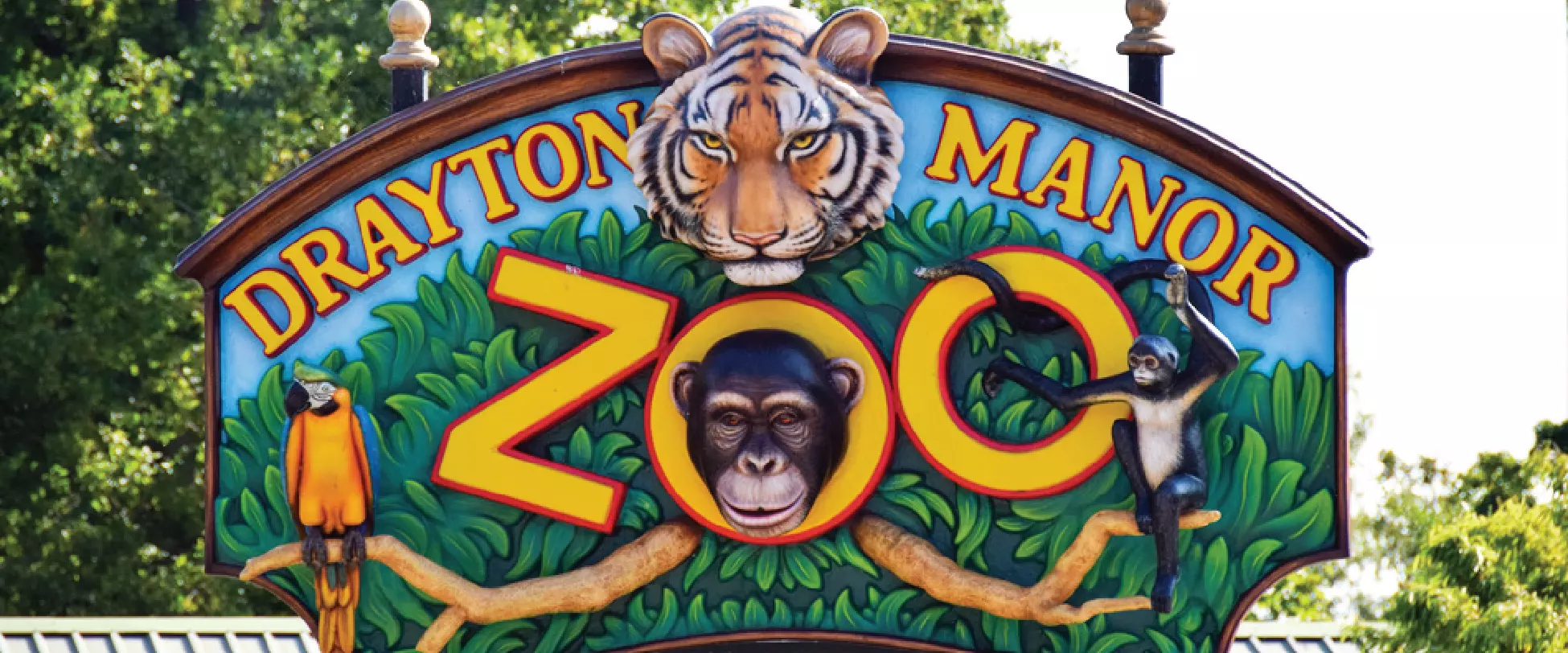 The sign for Drayton Manor Zoo featuring a parrot, tiger, and two monkeys..